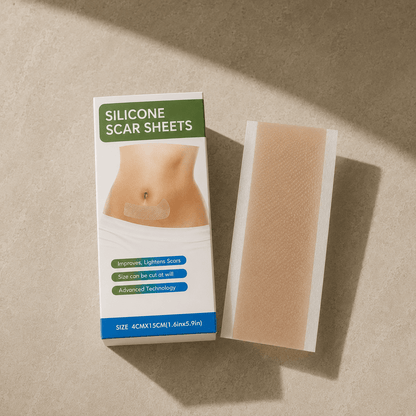 Verpackung mit der englischen Aufschrift „Silicone Scar Sheets, Size 4cm x 15cm" neben einem einzelnen hautfarbenen Silikonstreifen auf hellem Steinuntergrund.