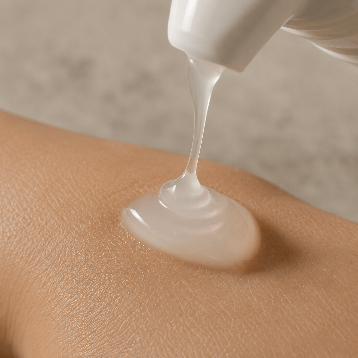 Nahaufnahme: ein Tropfen weißes Gel läuft aus dem Pumpspender auf die Haut.